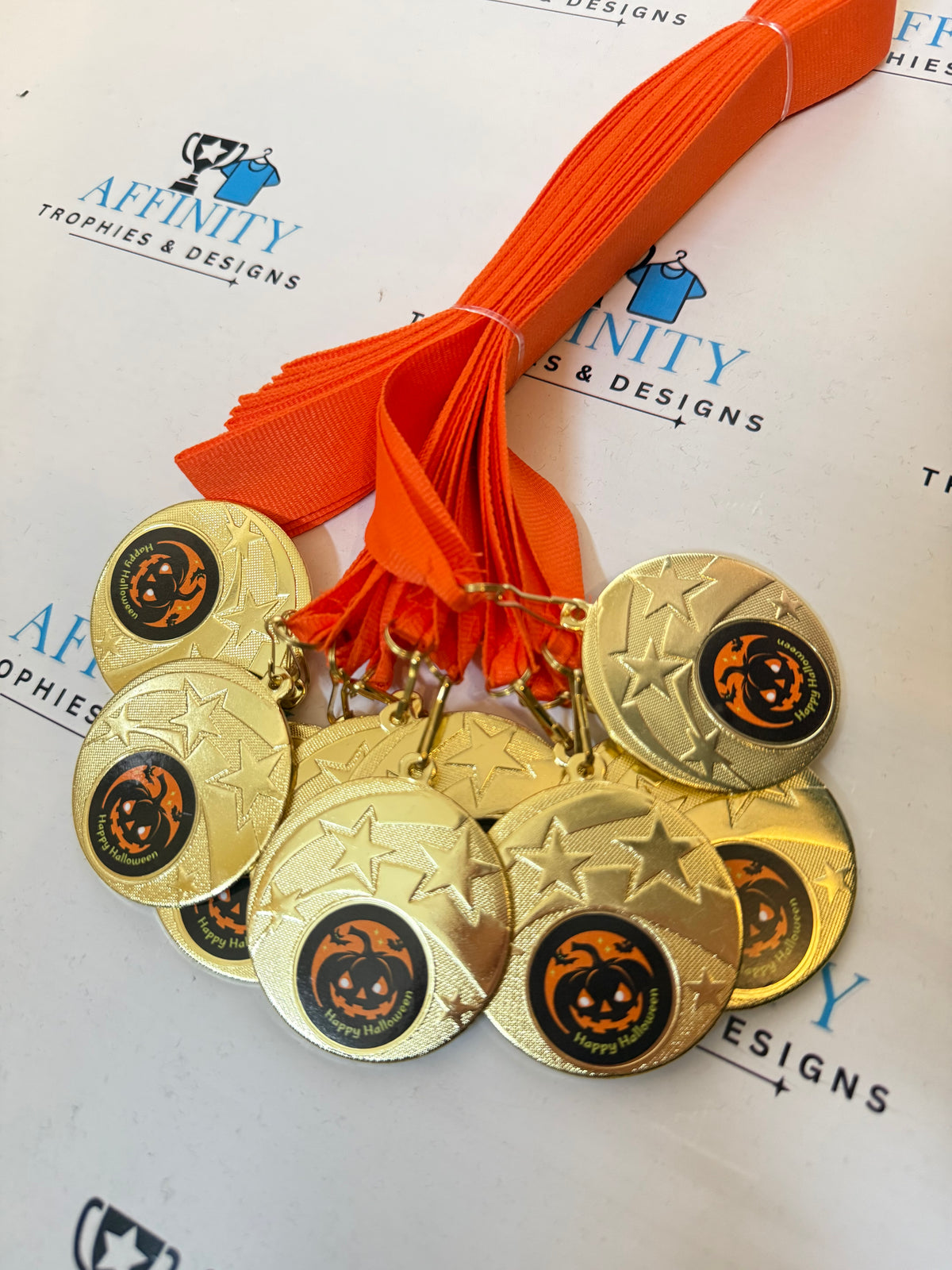 Gold-coloured Halloween medals with pumpkin centres and orange ribbons